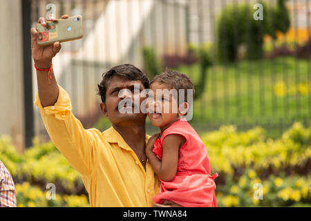 Bangalore, Karnataka India-June 04 2019: Vater und kleinen niedlichen Tochter unter Bild oder selfie mit Handy oder Handy Kamera auf touristische pl Stockfoto