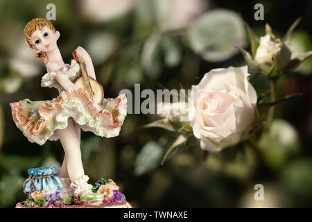 Jahrgang Mädchen Figur trägt Petticoat mit Guitarre und eine weiße Rose auf cremigen grünen Hintergrund. Zusammensetzung Stockfoto