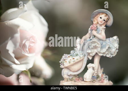 Jahrgang Mädchen Figur trägt Petticoat mit Bunny und eine weiße Rose auf Cremigem grünen Hintergrund. Zusammensetzung Stockfoto