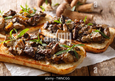 Toast mit gebratenen Steinpilzen, Zwiebeln, Thymian und Parmesan Nahaufnahme auf dem Tisch. Horizontale Stockfoto