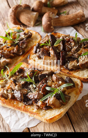 Sandwiches mit gebratenen Steinpilzen, karamellisierten Zwiebeln und Thymian close-up auf dem Tisch. Vertikale Stockfoto