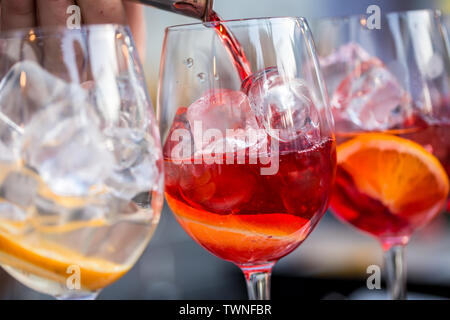 Gläser für Cocktails an der Bar. Der Barkeeper gießt aus einem Glas Sekt mit Aperol. . Restaurant Konzept Stockfoto