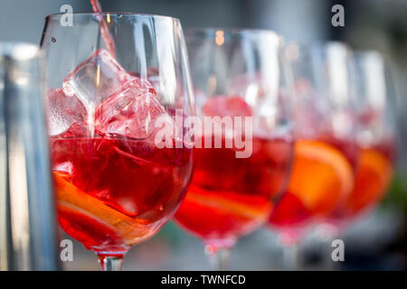 Gläser für Cocktails an der Bar. Der Barkeeper gießt aus einem Glas Sekt mit Aperol. . Restaurant Konzept Stockfoto