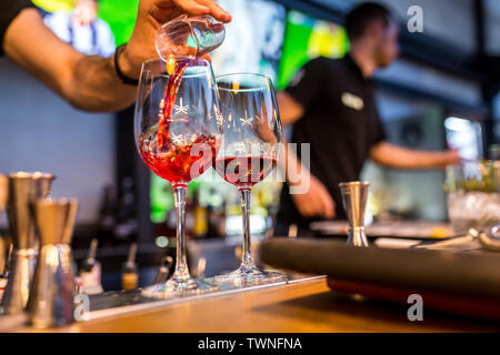 Gläser für Cocktails an der Bar. Der Barkeeper gießt aus einem Glas Sekt mit Aperol. . Restaurant Konzept Stockfoto