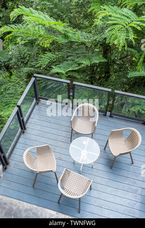 Stühle aus Holz mit Glas Tisch auf der Terrasse im tropischen Garten Stockfoto