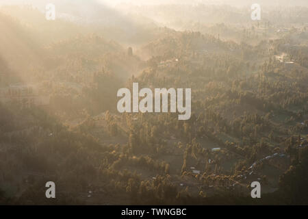 Oberhalb des Sonnenlichts auf tropischen Wald mit Nebel auf Dorf am Morgen Stockfoto