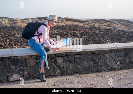 Reisen und Unabhängigkeit Personen Konzept mit blonden Schönen erwachsenen Frau mit der Planung der Reise mit Karte auf Papier und Rucksack auf dem Rücken - im Freien wilden Gegend hier is viel Stockfoto