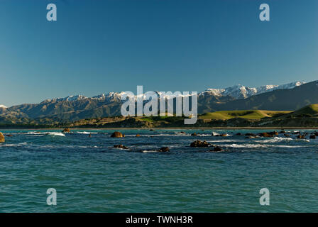 Eine schöne blaue grüne Meer setzt sich schneebedeckte Berge in Kaikoura, Neuseeland Stockfoto