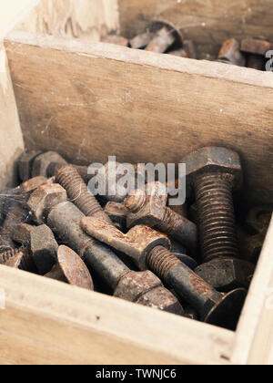 Rostigen Schrauben und Muttern in einem rustikalen hölzernen Kasten auf einer Werkbank, industrielle Close up Konzept Stockfoto