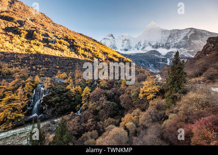 Mt. Jampelyang mit Wasserfall im Herbst Wald am Abend. Yading Nature Reserve, Daocheng, China Stockfoto