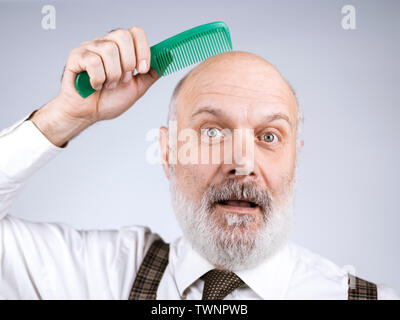 Lustige senior glatzköpfige Mann kämmt den Kopf und lächelte Kamera Stockfoto