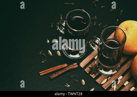 Wein mit Gewürzen und Orangen auf schwarzem Hintergrund Tabelle Glühwein. Retro Stillleben mit Kopie Raum Stockfoto