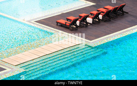 Lounge Sessel durch einen blauen Pool Stockfoto