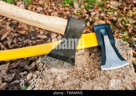 Zwei Achsen mit Stahlklingen in alter Baumstumpf im Herbst Laub Hintergrund klemmt Stockfoto