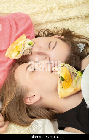 Überessen Mädchen Lügen mit Pizza Stücke im Mund Stockfoto