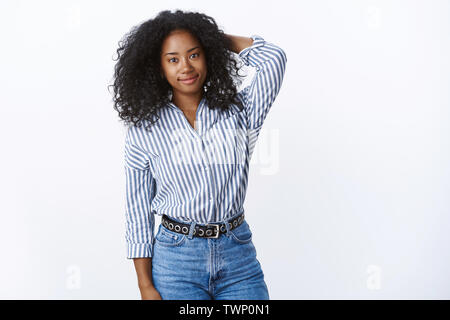 Attraktive schüchtern Ausschreibung african american Curly - behaarte Frauen Mitarbeiter die Hand hinter den Kopf unsicher unsicher lächelt freundlich Gefühl unangenehm, unkoordinierte Stockfoto