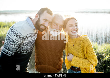 Porträt eines jungen Mannes und der Frau mit fröhlichen senior Großvater zusammen Umarmen im Freien, eine gute Zeit beim Fischen Stockfoto
