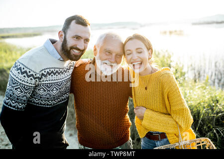 Porträt eines jungen Mannes und der Frau mit fröhlichen senior Großvater zusammen Umarmen im Freien, eine gute Zeit beim Fischen Stockfoto