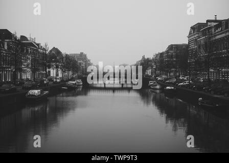 Charmantes Stadtbild der alten holländischen Stadt Haarlem. Steinerne Brücke verbindet zwei Ufer der Spaarne River. Schöne Perspektive. Neblig und bewölkt frühen sp Stockfoto