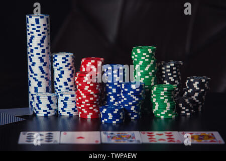 Close up Stack von verschiedenen farbigen Poker Chips und Karten auf den Tisch über schwarzen Hintergrund. Spielen Turnier für Wetten Stockfoto