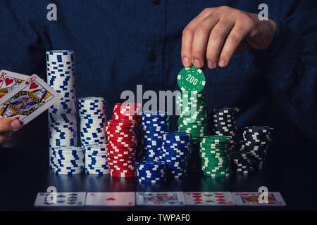 Der junge Mann poker Spieler Hände sichtbar Karten und Chips am Tisch. Spielen Turnier Sieger erfolg konzept über dunkle zurück Stockfoto