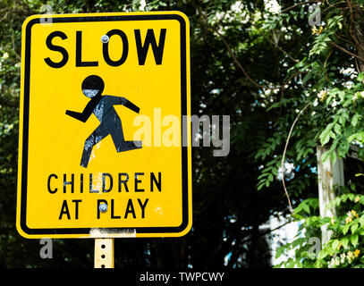 Ein gelbes Schild auf der Seite der Straße, verlangsamen Sie Kinder beim Spielen. Stockfoto