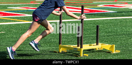 High School cros Land runner drückt eine schwere Schlitten über ein Rasenfeld suring Stärke Praxis. Stockfoto