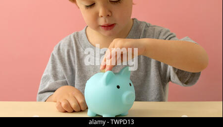 Little boy Münzen in einem Sparschwein Stockfoto