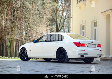 Grodno, Weißrussland, 16. Mai 2013: Moderner Luxus BMW 750Li XDrive Auto drei Viertel Blick auf Stein geparkt gepflasterte Parkplätze in der Nähe von Ancient House. Stockfoto