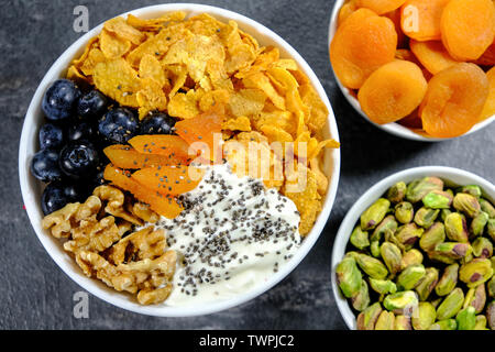 Gesundes Frühstück Schüssel Cornflakes, Joghurt, Aprikosen, Chia Samen, Nüsse und frischen Blaubeeren Stockfoto