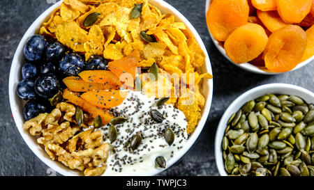 Gesundes Frühstück Schüssel Cornflakes, Joghurt, Aprikosen, Chia Samen, Nüsse und frischen Blaubeeren Stockfoto
