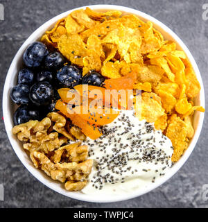 Gesundes Frühstück Schüssel Cornflakes, Joghurt, Aprikosen, Chia Samen, Nüsse und frischen Blaubeeren Stockfoto