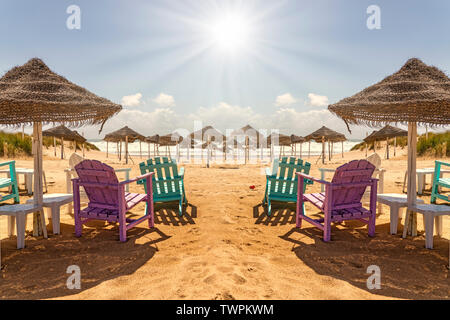 Farbenfrohe Stühle am Strand mit Blick auf die Sonne Stockfoto