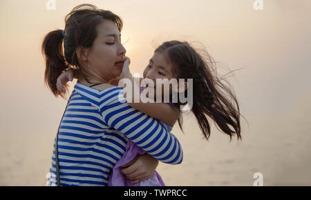 Schöner Moment mit Mama und Kind spielen und Umarmung mit Sonnenuntergang warmes Licht. liebe Familie zusammen Stockfoto