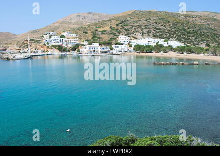 Blick über die Bucht auf die wunderschöne griechische Insel Sikinos. Der Sandstrand führt zum Hafen der Insel, wo weißgetünchte Gebäude den Hafen säumen. Stockfoto