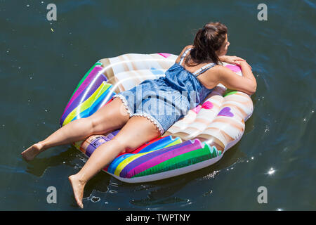 Iford, Dorset, Großbritannien. Am 22. Juni 2019. Perfektes Wetter, warm und sonnig, noch für Dorset Beiboot Tag mit Hunderten von Schlauchboote, Faltboote, Handwerk, Platten bilden eine Flottille Segeln von iford Brücke, den Fluss Stour zu Tuckton Brücke. Die Veranstaltung begann im Jahr 2014 als ein wenig Spaß, aber hat jetzt eine jährliche Veranstaltung Geld für Nächstenliebe und Getter jedes Jahr größer geworden. Junge Frau entspannend auf aufblasbaren Cupcake aufblasbar. Credit: Carolyn Jenkins/Alamy leben Nachrichten Stockfoto