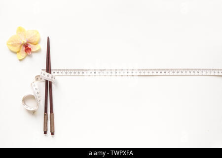 Asiatischen Ernährung Konzept. Stäbchen und Maßband auf weißem Hintergrund, kopieren. Diät, asiatische gesunder Lebensstil, Gewichtsverlust Konzept. Stockfoto