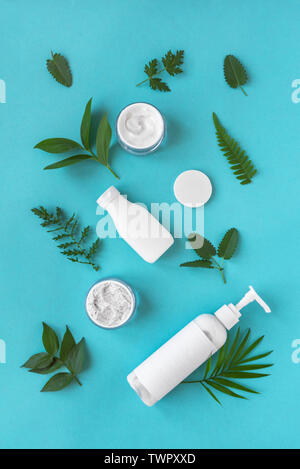 Naturkosmetik und grüne Blätter auf blauem Hintergrund, Ansicht von oben, flach. Natürliche organische Hautpflege, Bio Forschung und gesunden Lebensstil Konzept. Stockfoto