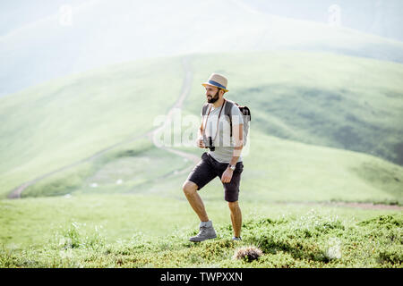 Menschen wandern mit Rucksack auf der schönen, grünen Wiese unterwegs in den Bergen während der sonnigen Wetter Stockfoto