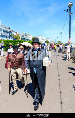 Jährliche Broadstairs Dickens Festival. Die wichtigsten Parade an der Strandpromenade, mit Menschen, die in der viktorianischen Kostüm wie Dickensian Zeichen gekleidet. Mann in voller schwarzen Anzug und Hut, die andere in Richtung Betrachter. Stockfoto