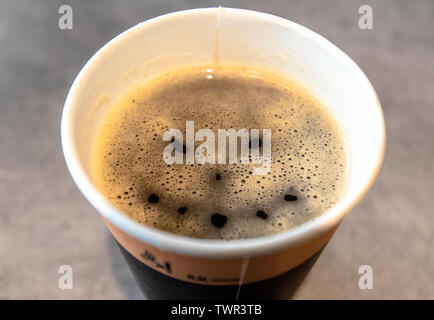 Wütend das Gesicht auf der Oberfläche der Kaffee im Pappbecher - konzeptionelle Bild Kaffee als Droge Stockfoto