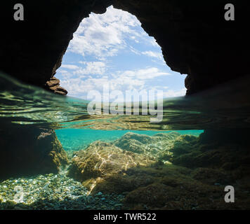 In einer Höhle am Meer, blauer Himmel mit Wolken und Felsen unter Wasser, geteilte Ansicht Hälfte über und unter Wasser, Mittelmeer, Spanien, Costa Brava Stockfoto