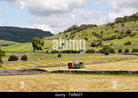 Die Landwirte profitieren Sie von einem Tag auf trockener Sommer Wetter Mähwiesen zu schneiden und das Gras sammeln für Silage, Austwick, North Yorkshire. Stockfoto