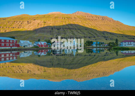 Perfekte Wasser Reflexion, perfekte gespiegeltes Bild einer Isländischen fjord Stadt im Wasser, sunrise Reflexion mit perfekten Berg Schatten im Fjord Stockfoto