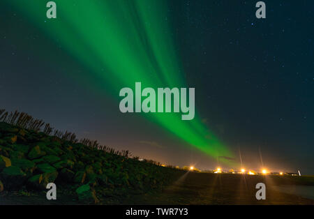 Eine grüne Streifen von Aurora Borealis, Bauchspeck northern lights aus die Lichter der Stadt. Blue Arctic Sky mit Aurora und die Lichter der Stadt. Stockfoto