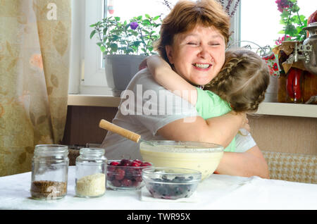 Portrait von Gesichtern, Händen glücklich Braunhaarige granny Hug Enkelin. Kleinkind Mädchen spielen mit Großmutter auf Küche. Kind Baby halten Oma und Lachen Stockfoto