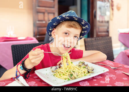 Freundliche kleine Junge genießen Meeresfrüchte Pasta zum Mittagessen im italienischen Restaurant Terrasse Stockfoto