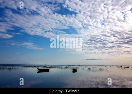 Kleine Fischerboote vor Anker, in der ruhigen und klaren Wasser des Sees spiegelt, sind mit Schilf am frühen Morgen gegen die schöne Dämmerung Himmel von sanften Pastelltönen abgedeckt. Stockfoto