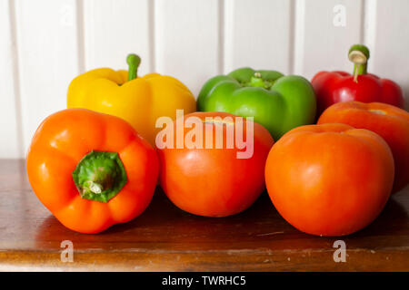 Gelb, Grün, Rot und Orange Paprika mit drei reife, rote Tomaten Stockfoto