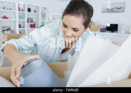 Frau zu Hause auspacken eine Lampe aus einem Karton Stockfoto